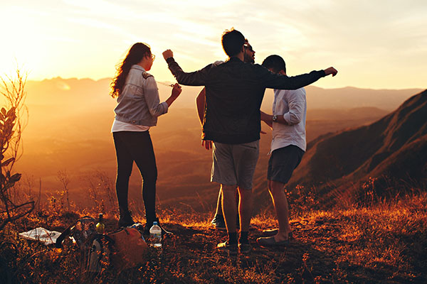 Four people standing up on top of a mountain and having a picnic