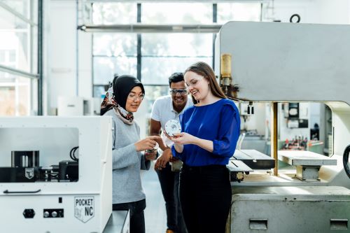 Three people in a lab, examining a piece of equipment