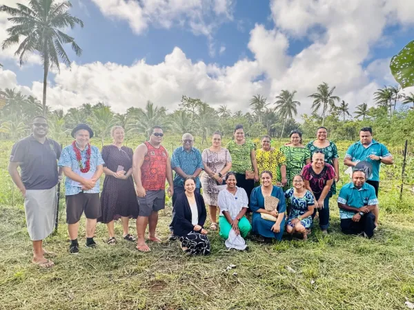 Group of people posing in front of a field of crops