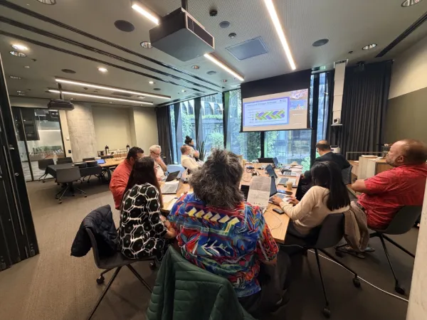 People sitting around a meeting looking to a projection screen.