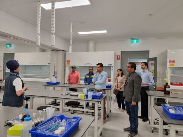 PhD student showing 6 people around a lab room.